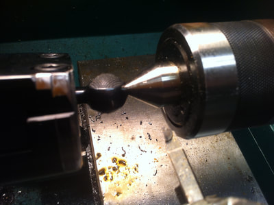 Bolt is inserted in a jig in the lathe, a small pilot hole is drilled into bottom of the bolt so the tail stock can hold the bolt in place 